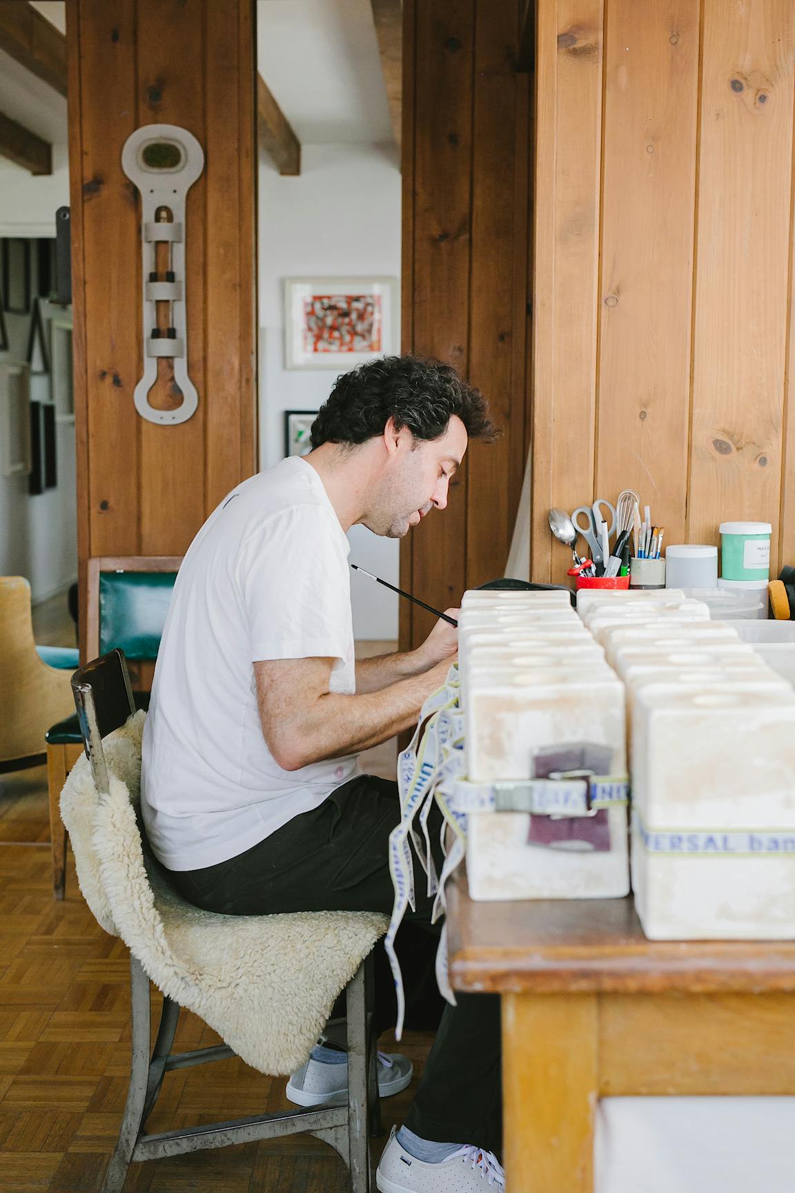 A person works at a desk next to ceramic molds.